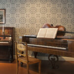 Sibeliuksen syntymäkodin isännänhuone. Vasemmalla piano, oikealla taffelipiano. Soittimien edessä tuolit, nuottitelineillä nuotteja. Taffelipianon päällä sello.