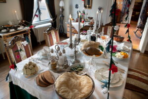 Palanderin talon ruokasalin runsas joulupöytä kinkkuineen, perunavanukkaineen, rosolleineen, kynttilöineen ja ruusukkeineen