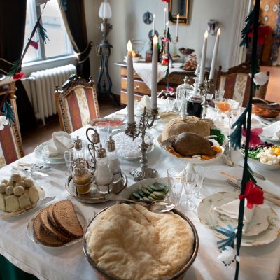 Palanderin talon ruokasalin runsas joulupöytä kinkkuineen, perunavanukkaineen, rosolleineen, kynttilöineen ja ruusukkeineen