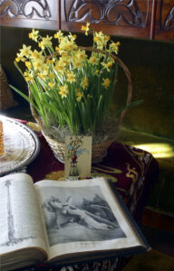 Palanderin talon herrainhuoneen pöydällä narsisseja korissa, pääsiäiskortti ja avonainen Raamattu.