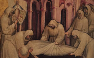 Kuusi hupullisiin kaapuihin pukeutunutta henkilöä laskee kankaaseen käärittyä ruumista arkkuun. Taustalla kirkko. Valokuva maalauksesta.