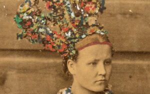 Naishenkilö, jolla värikäs ja koristeellinen korkea päähine päässä.