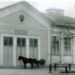 Vaalea kivirakennus, jossa kolmet pariovet. Pariovien edessä seisoo hevonen rattaineen. Ovien yllä teksti Teatteriravintola Teater restaurant.