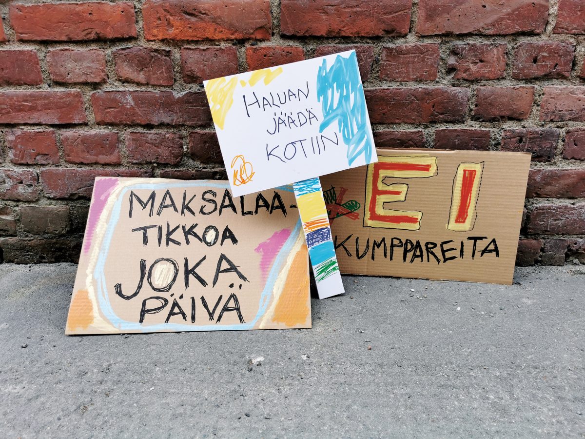 Hippaloiden mielenosoitustyöpajan mainoskuva: Kolme värikästä pahvista tehtyä mielenosoituskylttiä, joissa lukee "Maksalaatikkoa joka päivä", "Haluan jäädä kotiin" ja "Ei kumppareita". 