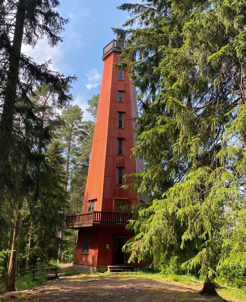 Kaukolanharjun puinen punainen näkötorni kuusten ja mäntyjen keskellä