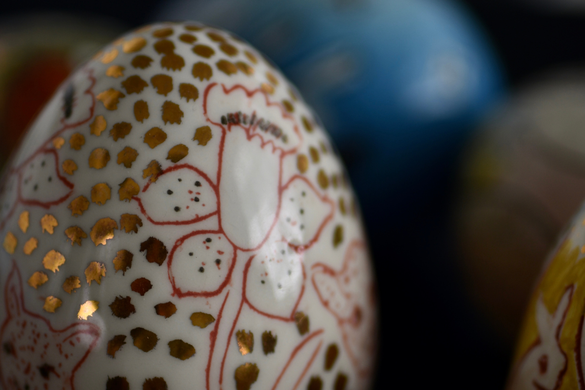 Lähikuva Heljä Liukko-Sundströmin keramisesta munasta. Väritykseltään valkoinen ja punainen. Kuvioinnissa kukka.