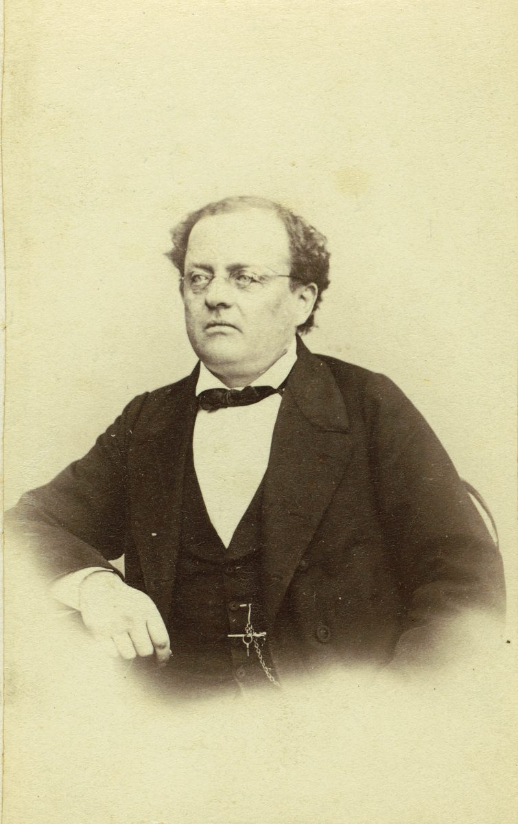 Kellastuneessa mustavalkoisessa valokuvassa mies 1800-luvun puvussa istuu katsoen ohi kuvaajasta. 