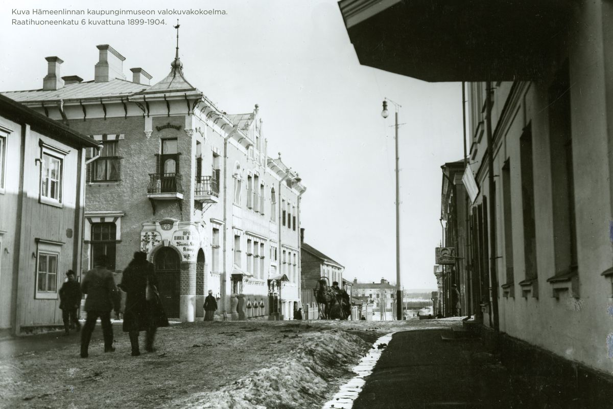 Keväinen katu 1800-luvun lopussa. Ihmisiä ja hevoskärryt loskassa.